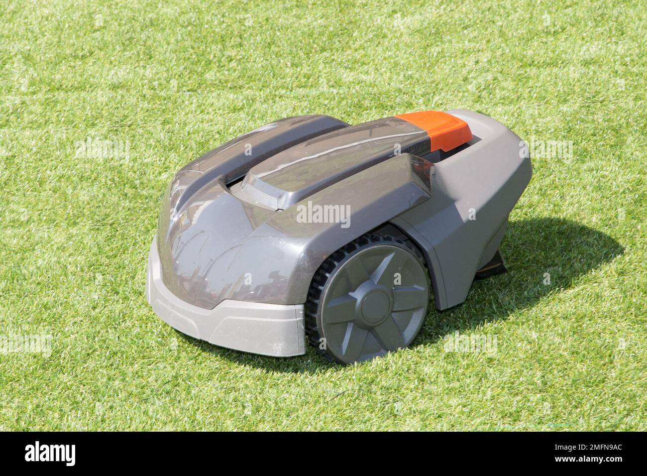 grey green autonomous electric lawn mower in garden cut grass Stock