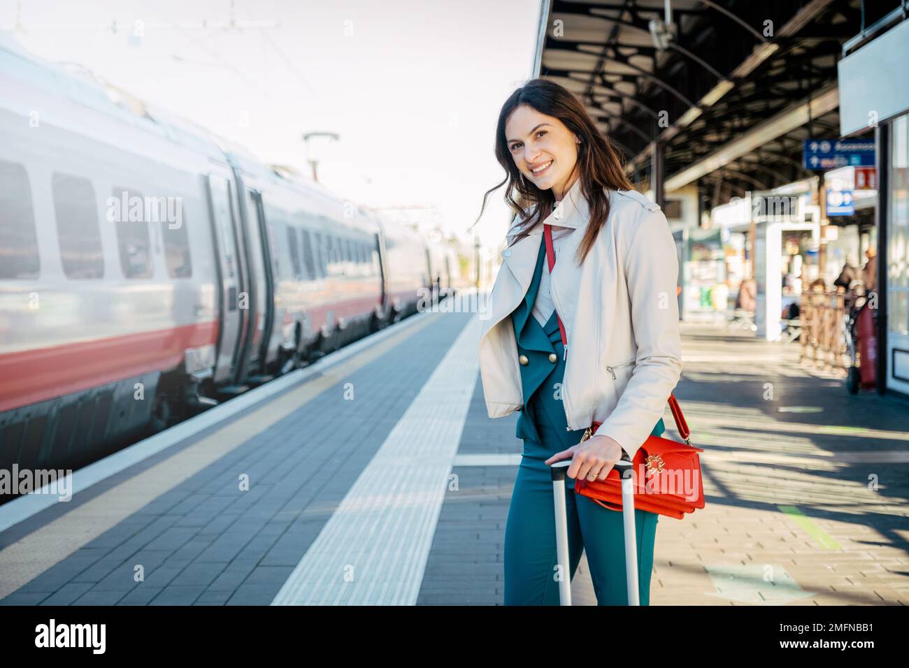 Portrait of a business woman commuter walking in a train station or airport going to boarding gate with hand luggage Stock Photo