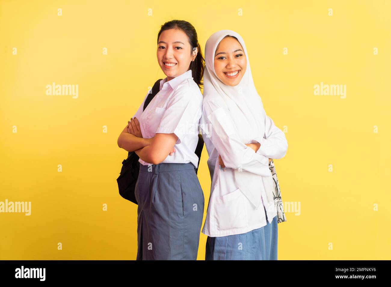 two high school girls standing back to back carrying bags Stock Photo ...