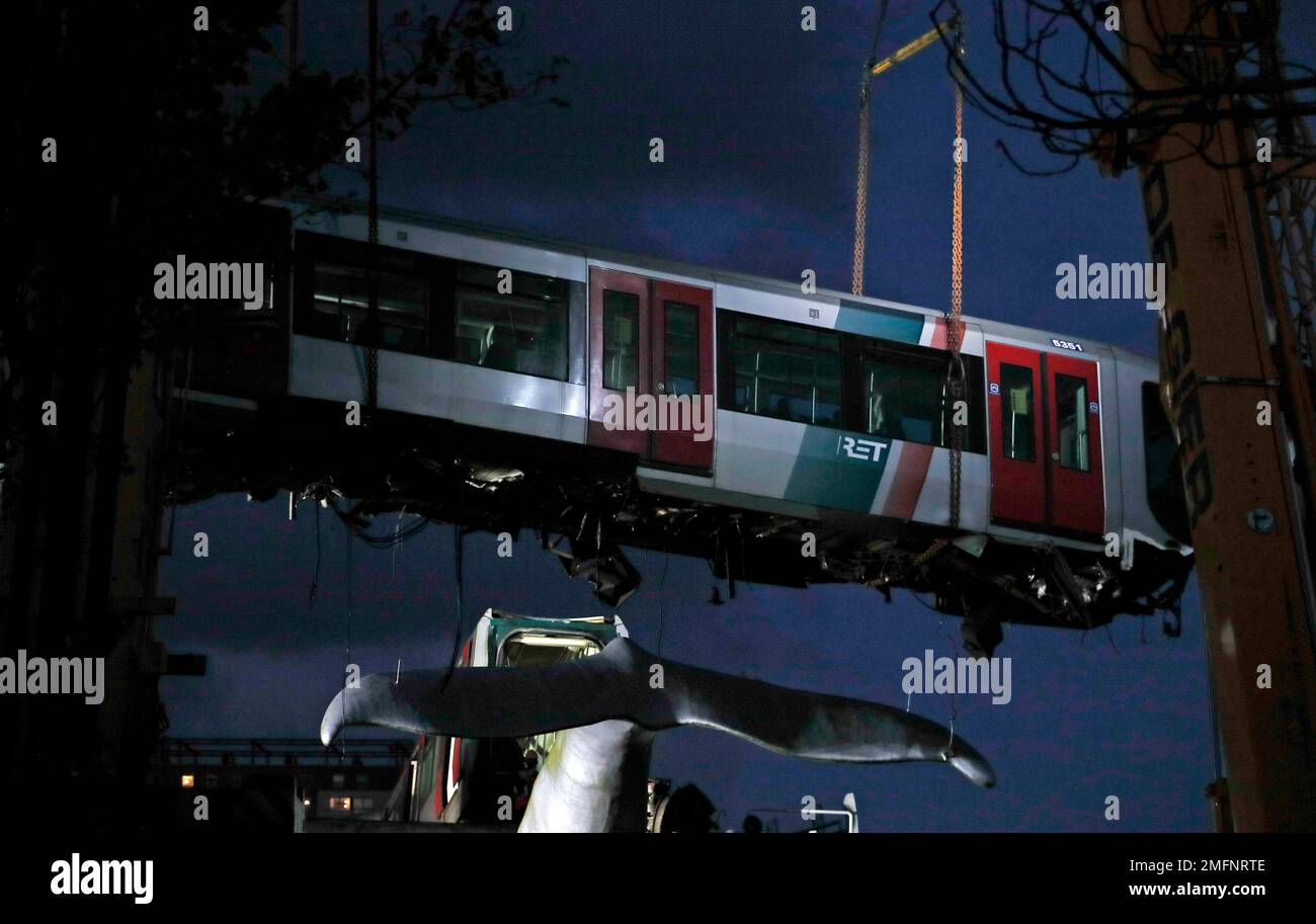 A salvaging crew uses a crane to lift a metro train carriage off of the