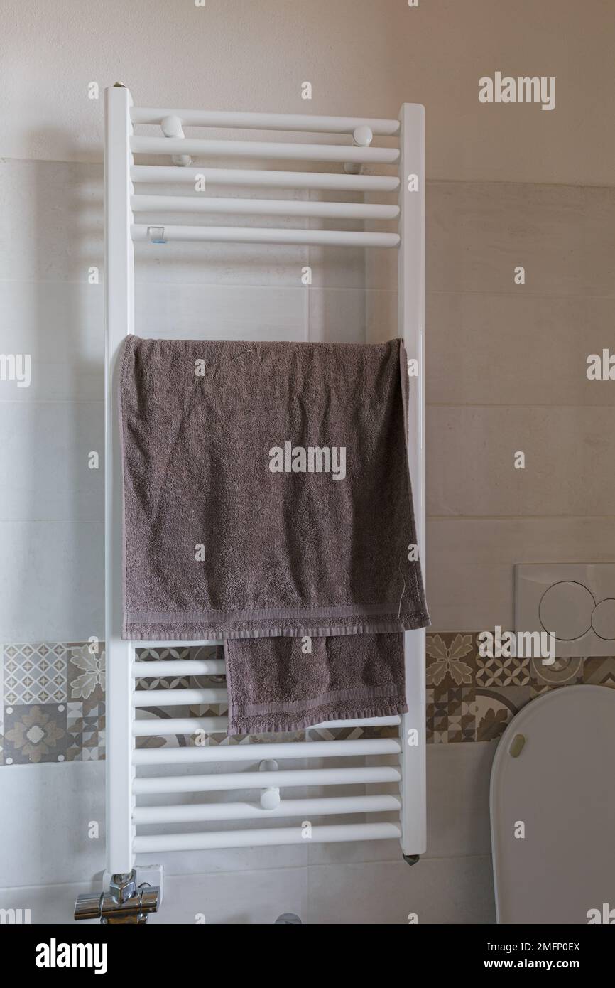 A sleek, towel warmer affixed to a pristine, tiled bathroom wall, Stock Photo