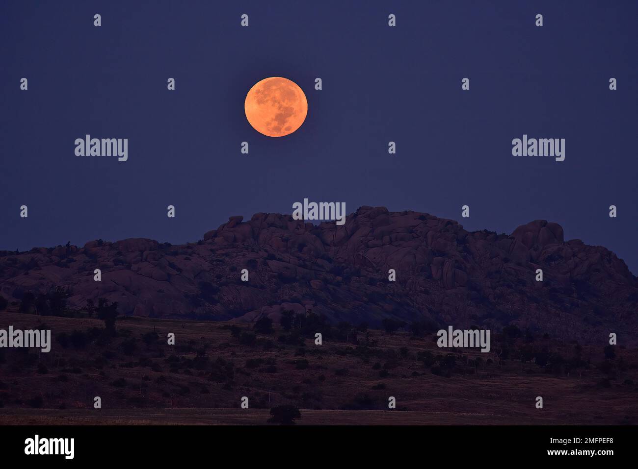 Full moon setting behind mountains, Wichita Mountains Wildlife Refuge, Oklahoma Stock Photo