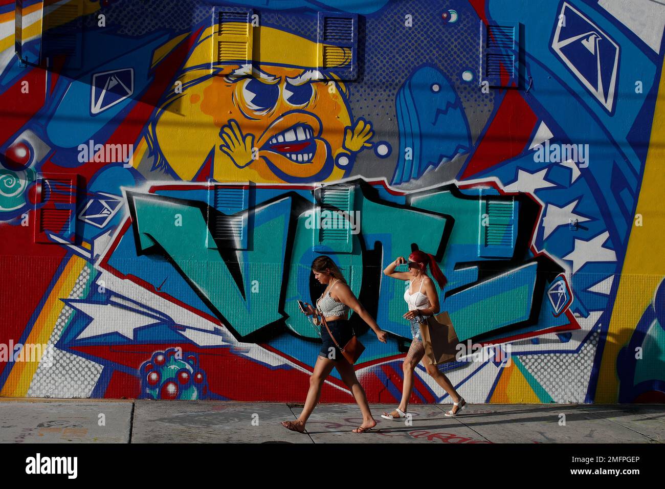 People walk past an election-themed mural by artist Mr. Ewok One, outside the Museum of Graffiti in Wynwood, Miami, Friday, Oct. 30, 2020.(AP Photo/Rebecca Blackwell) Stock Photo