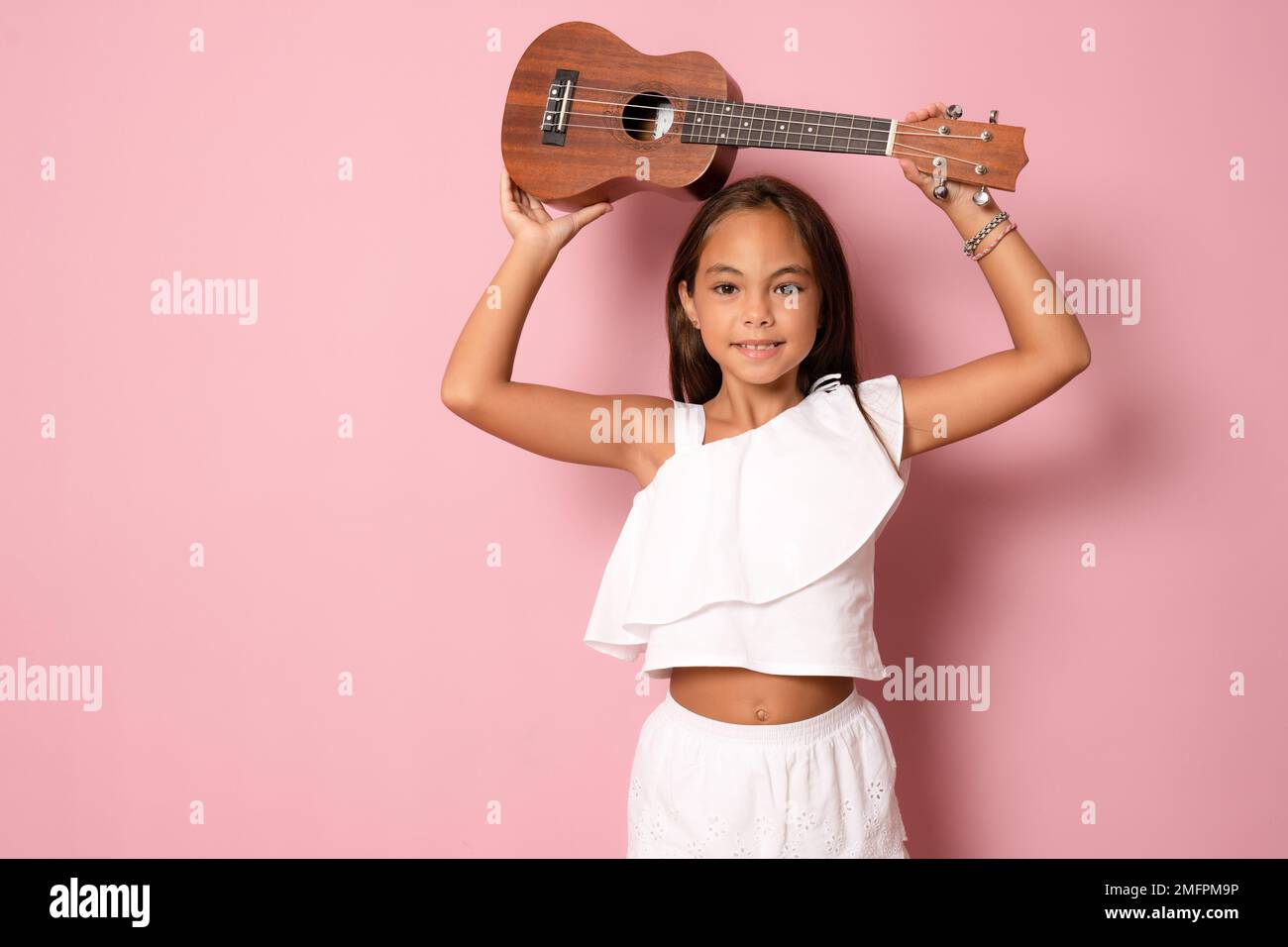 Cute little girl in summer clothing playing ukulele over pink background.  Happy vacation concept Stock Photo - Alamy