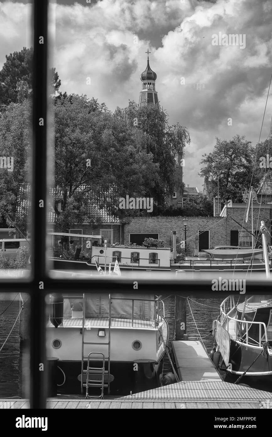 Enkhuizen, Netherlands - August 18,2021: View from the window to the harbor and moored sailboats. In the background, the dome of the church and stunni Stock Photo