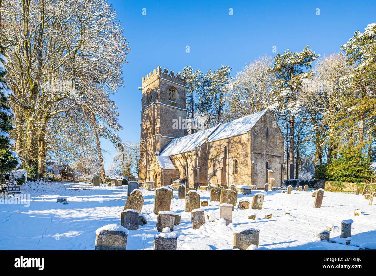 Early winter snow at the church of St John the Evangelist in the Cotswold village of Elkstone, Gloucestershire, England UK Stock Photo