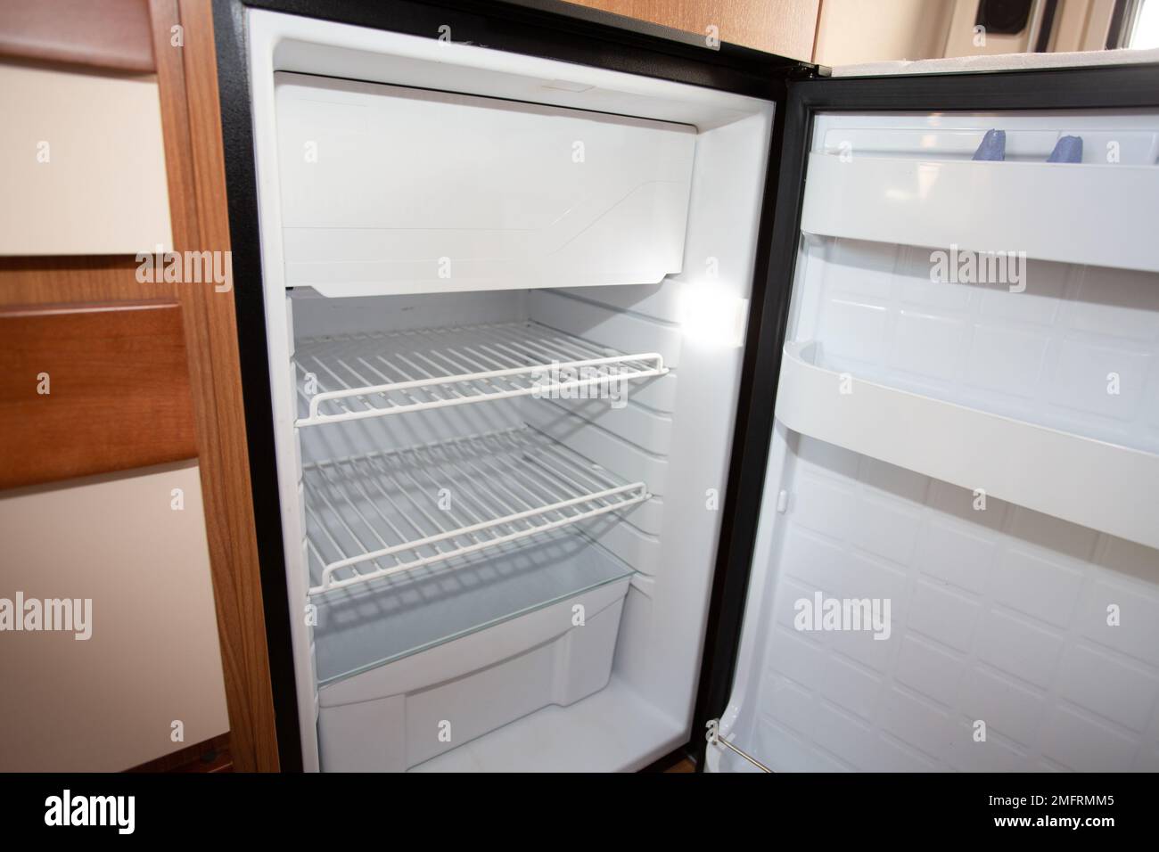 Camper van interior with the small fridge open in vanlife on road with motor home Stock Photo