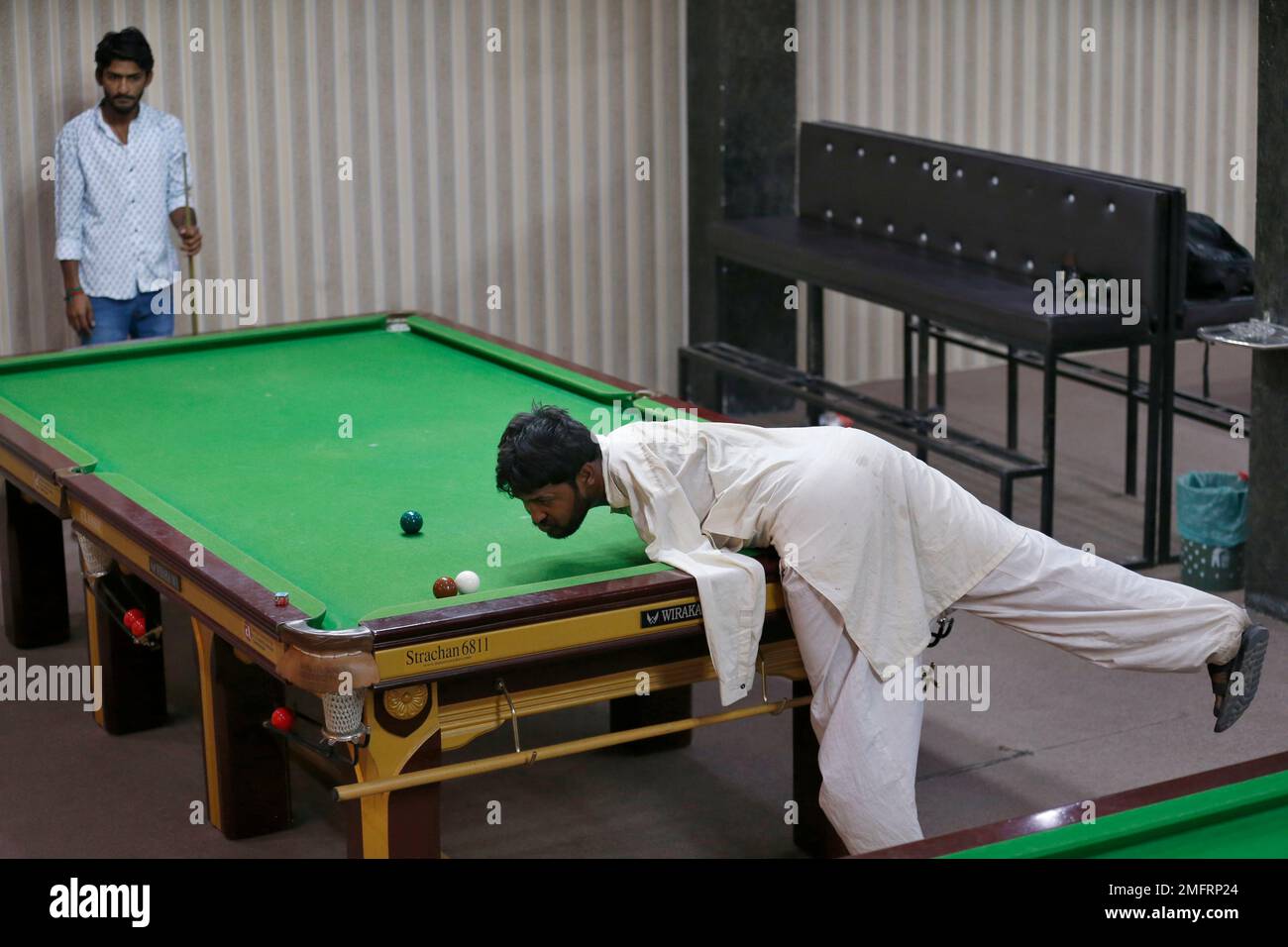 Mohammad Ikram plays snooker with his chin at a local snooker club in Samundri town, Pakistan, Sunday, Oct