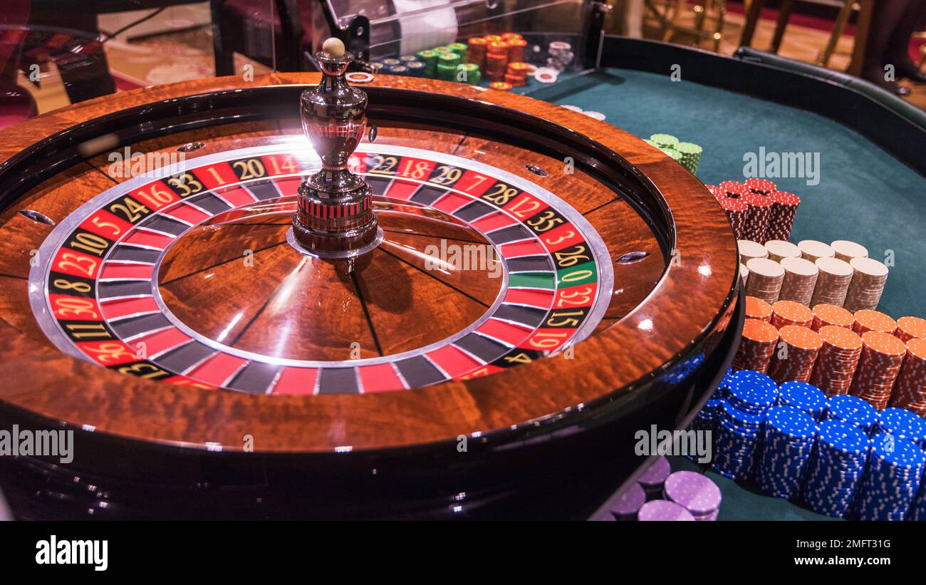 Casino, gambling and entertainment concept - roulette table and stack of poker chips Stock Photo
