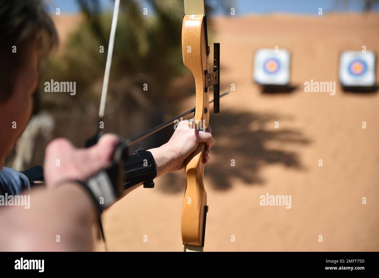 Woman doing archery in the desert of Dubai, United Arab Emirates Stock