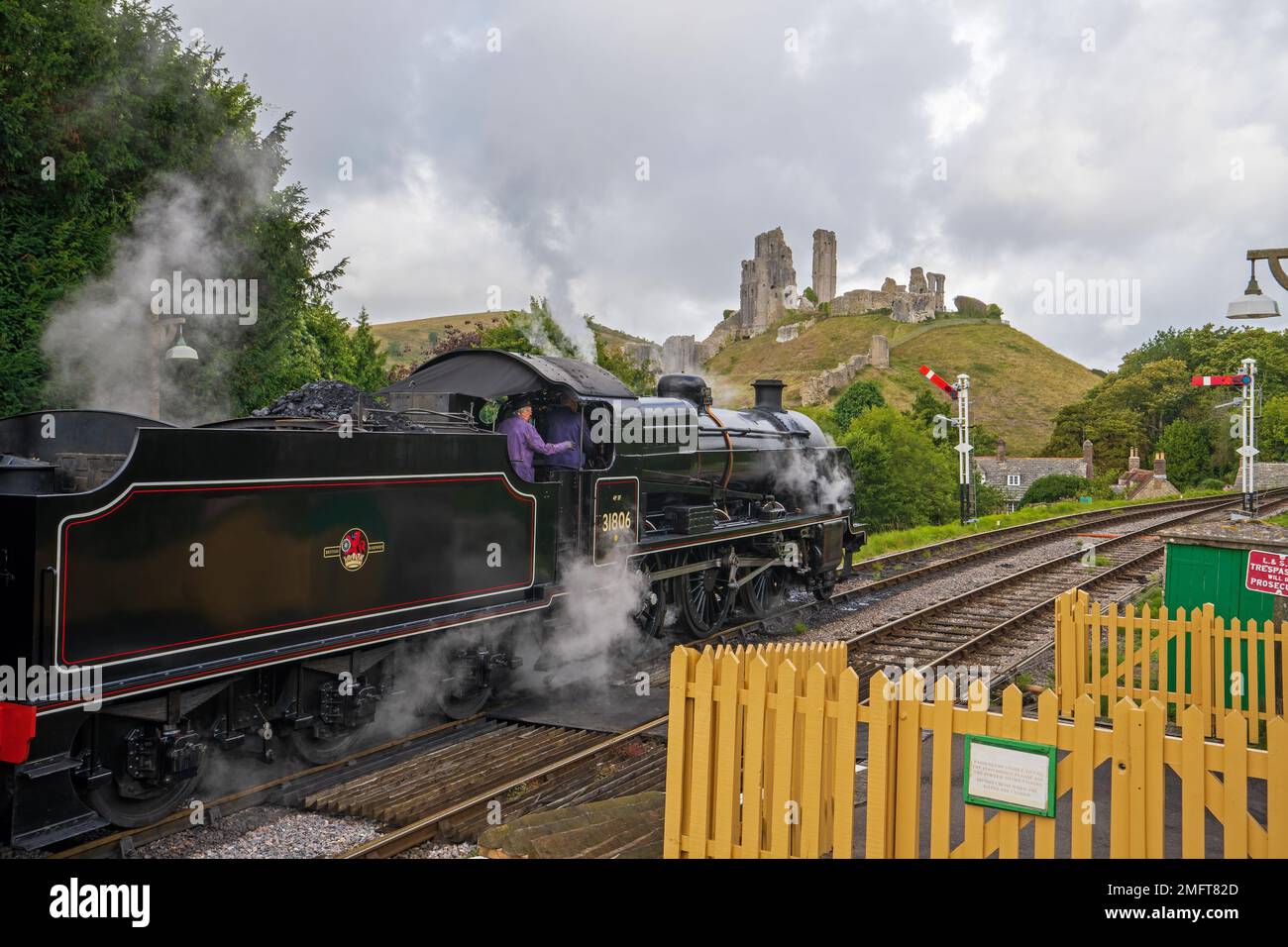 The SR U Class steam locomotive 31806 passes Corfe Castle on the Swanage Railway, as it travels between Corfe Castle station to Norden. Corfe, Dorset, Stock Photo