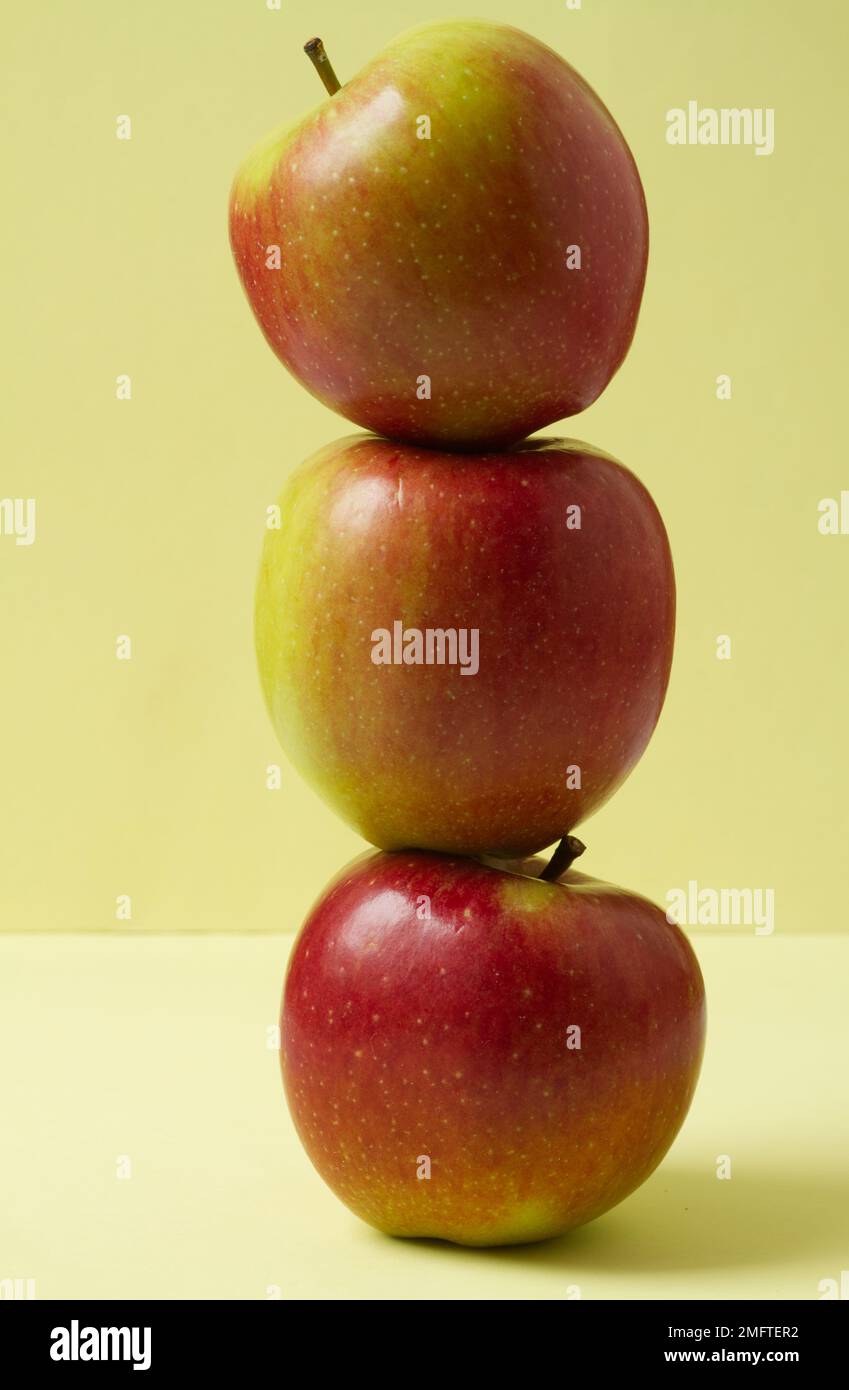 Close up of three Braeburn apples stacked one on top of the other against a plain background Stock Photo