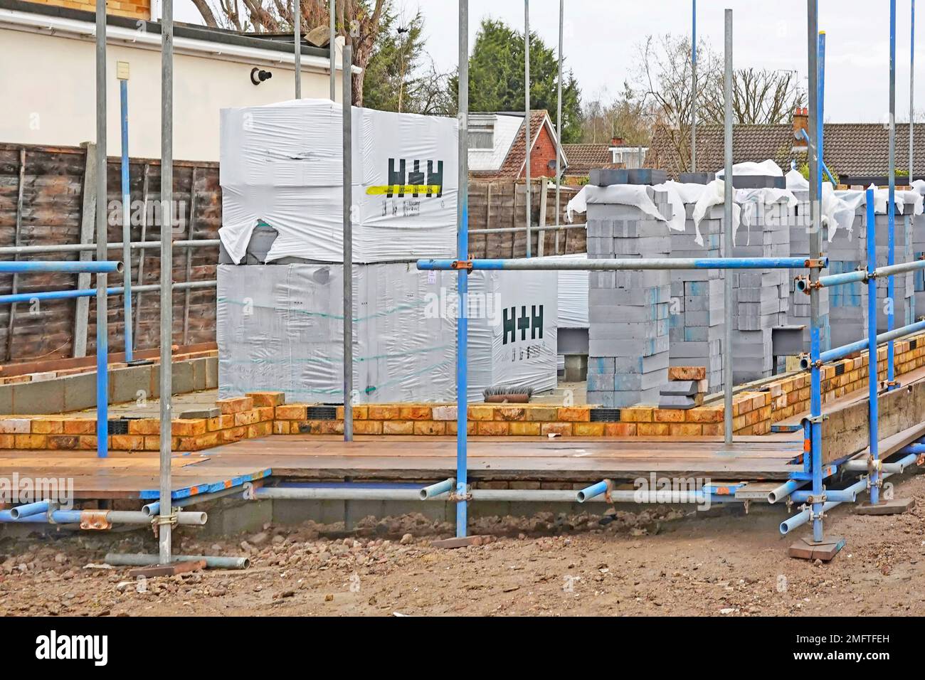 Insulating building blocks by Aircrete H+H Celcon plastic wrapped stacked for bricklayers to build inner skin of cavity wall in new detached house UK Stock Photo