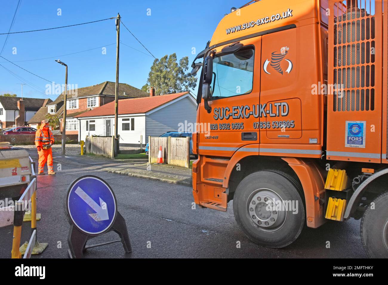 Hgv lorry truck driver in residential street slowly moving large suction excavation machine by remote control for gas main replacement work England UK Stock Photo