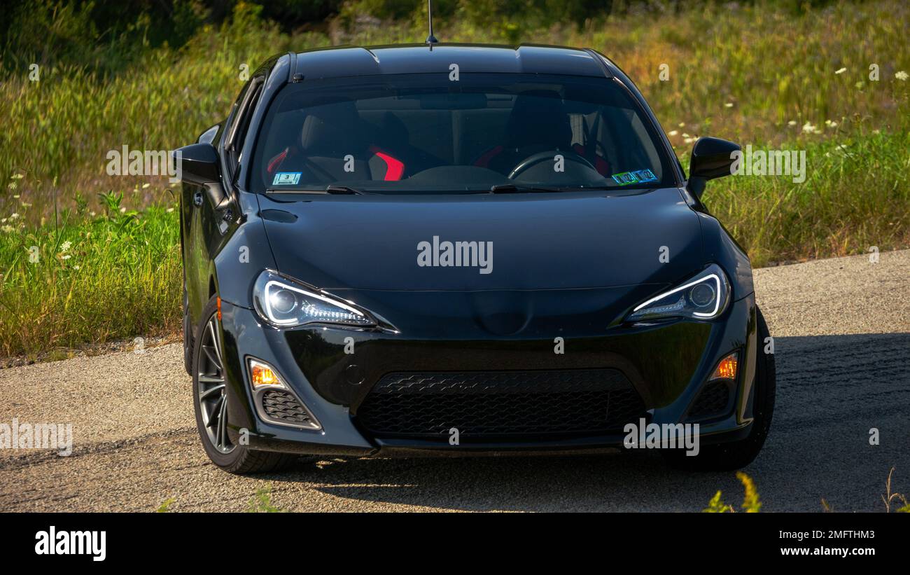 A jet-black two-door Scion car on the road. Stock Photo