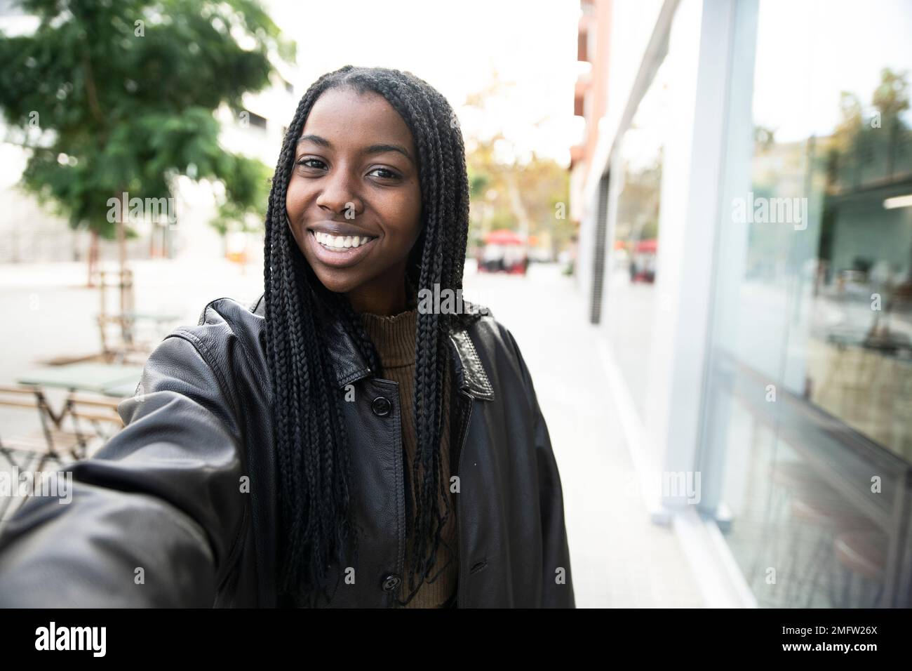 happy young woman smiling taking a selfie portrait in the city - portrait of young afro american woman taking a selfie outdoor Stock Photo