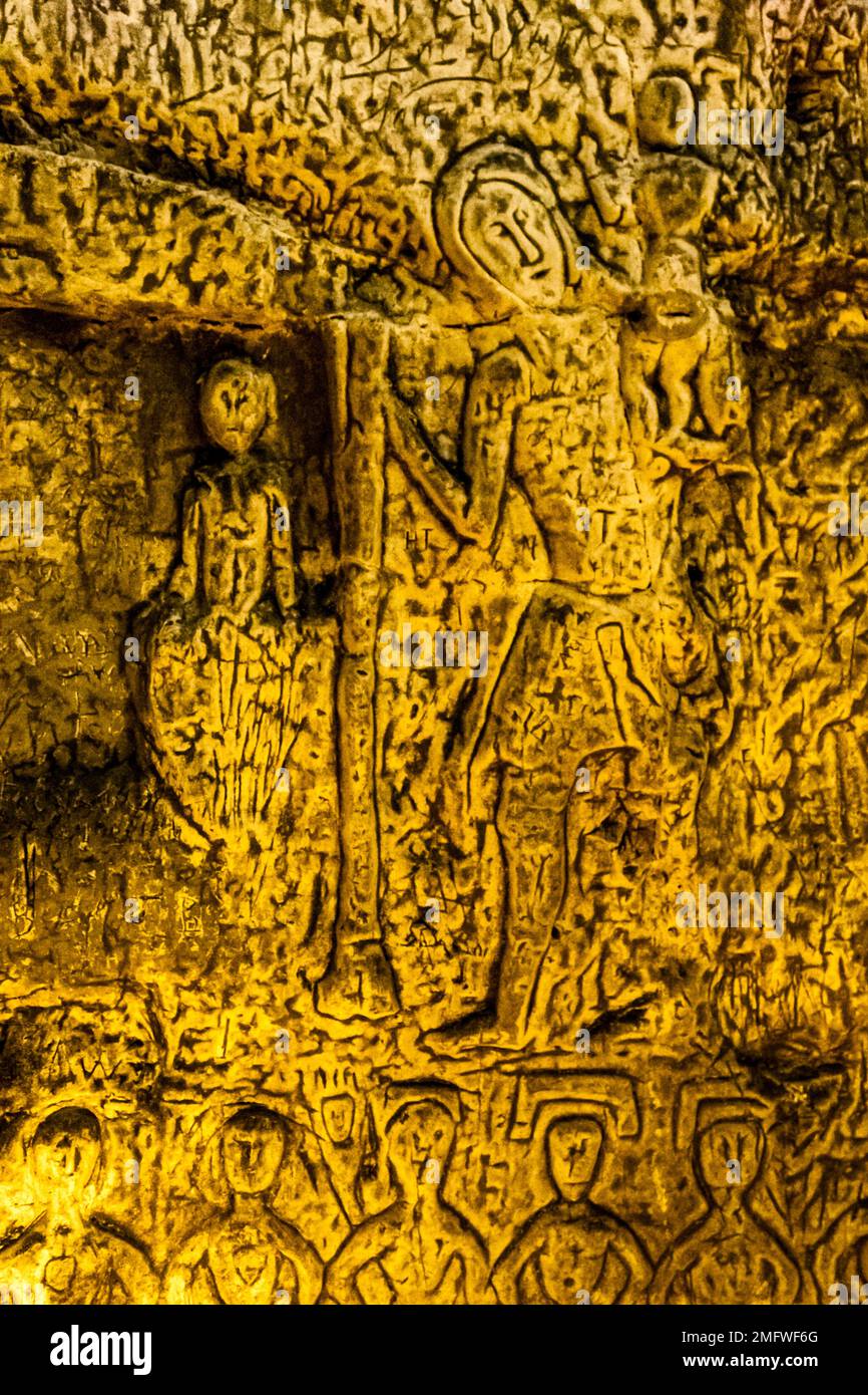 One of the great Christian carvings in Royston Cave is St. Christopher. He is the patron saint of travelers. He is depicted as a giant with a staff and the baby Jesus on his shoulder. The invocation of St. Christopher was supposed to protect from sudden death. Royston Cave in Katherine's Yard, Melbourn Street, Royston, England Stock Photo