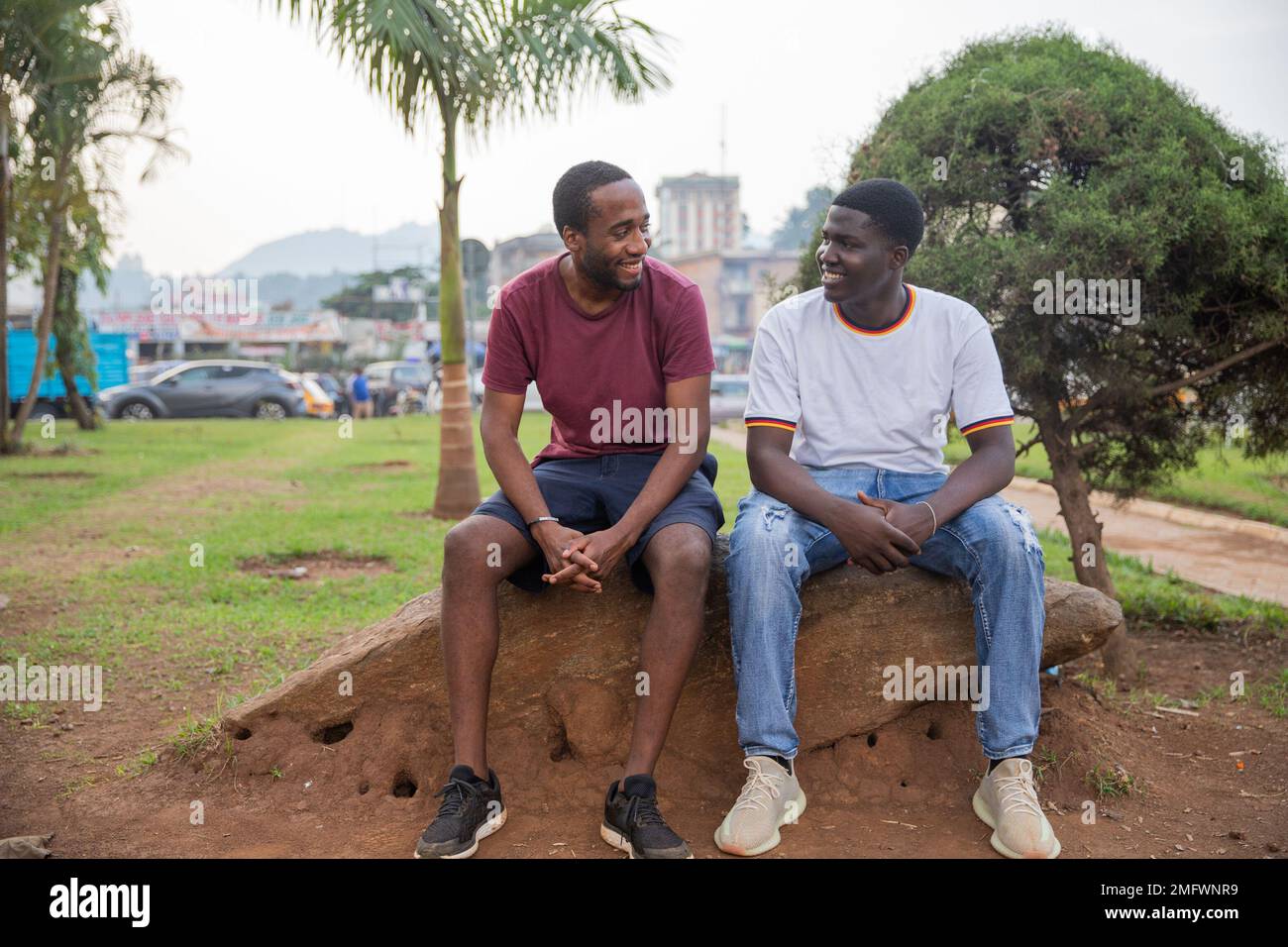 Two friends laugh as they look at each other in a public park in Africa Stock Photo