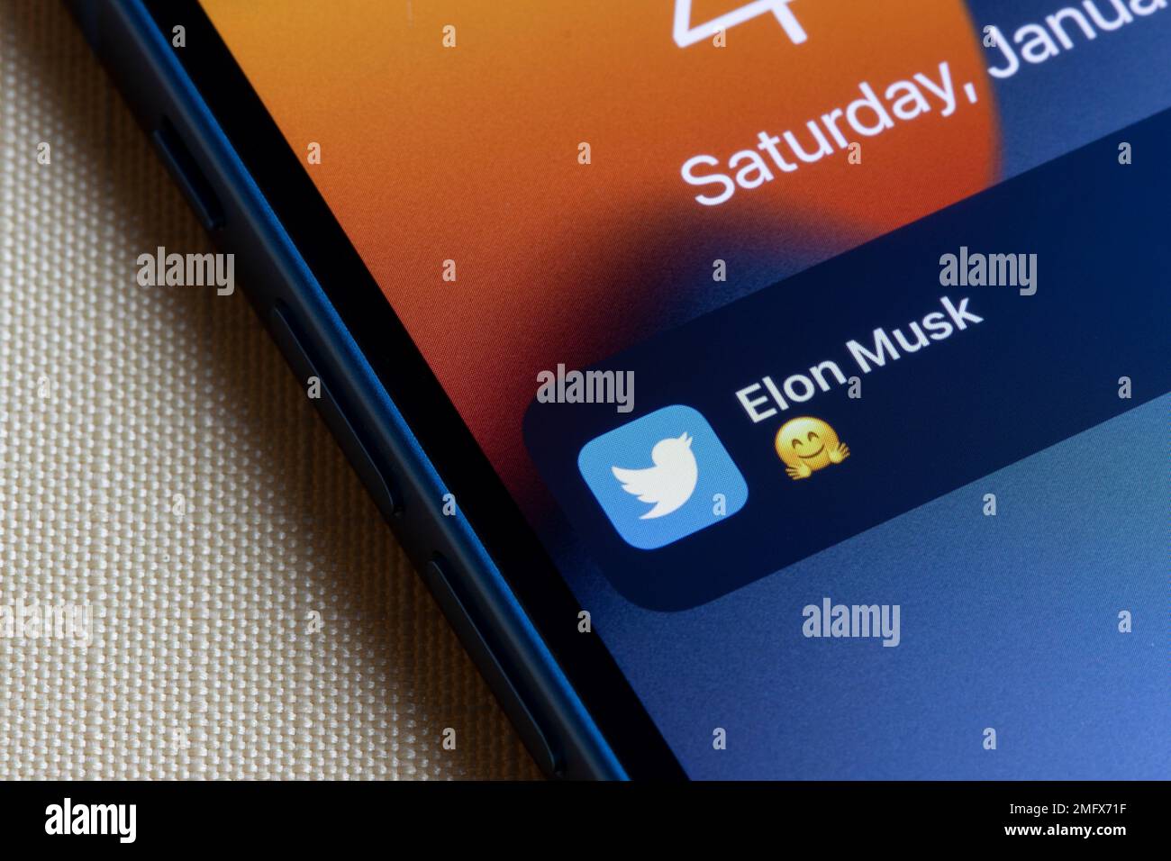 Notification of a new tweet from Elon Musk with a hugging face emoji is seen on the lock screen of an iPhone. Elon Musk's Twitter takeover concept. Stock Photo