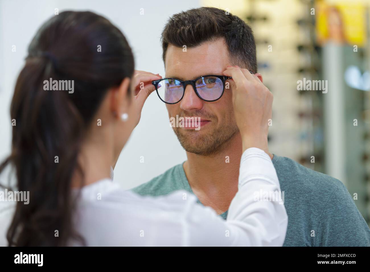 man trying on glasses in optical store while smiling Stock Photo Alamy
