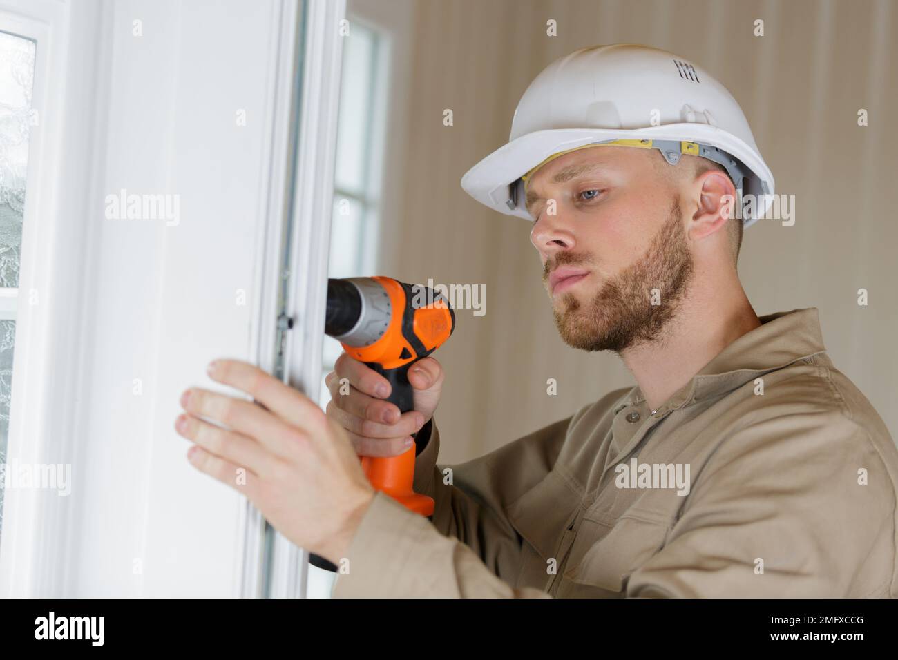 construction worker using drill to install window Stock Photo - Alamy