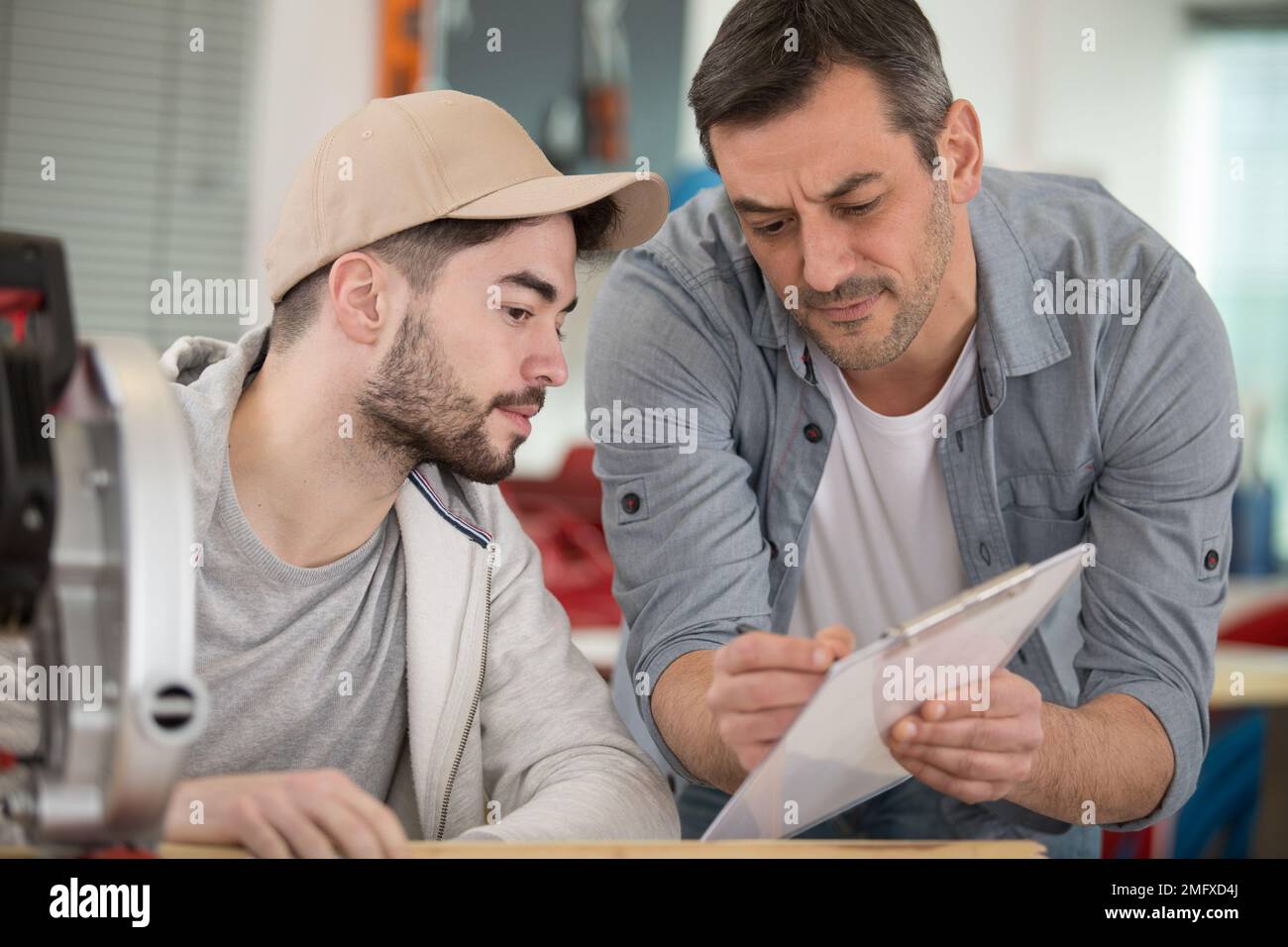 supervisor in discussion with apprentice looking at clipboard Stock Photo