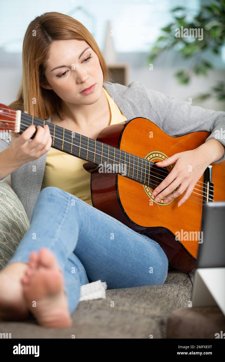 pretty girl legs crossed playing some record on guitar Stock Photo Alamy