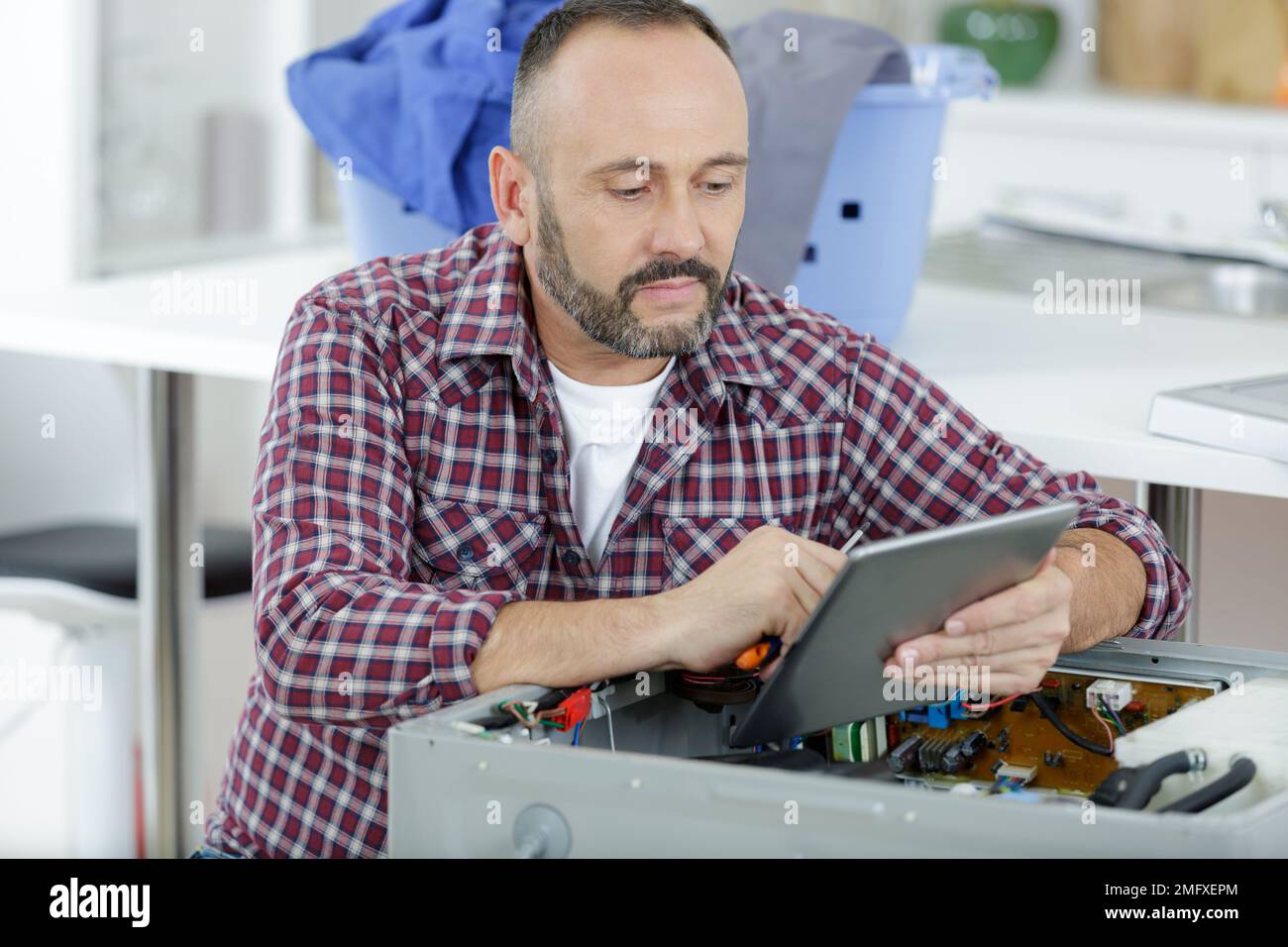 serviceman using tablet to diagnose and repair appliance Stock Photo