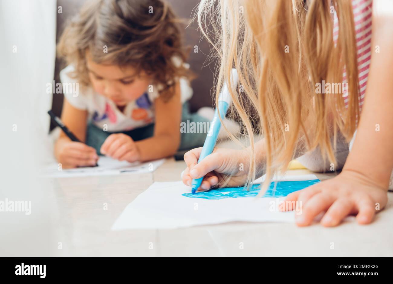 Cute little children girls lying on floor and drawing with color ...