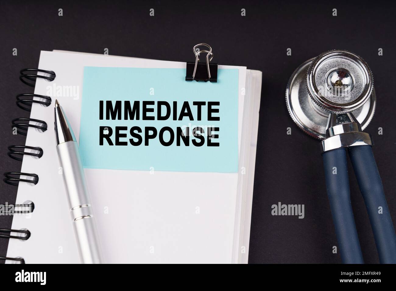 Medical concept. On a black surface, a stethoscope, a notebook, a pen and a blue sticker with the inscription - IMMEDIATE RESPONSE Stock Photo