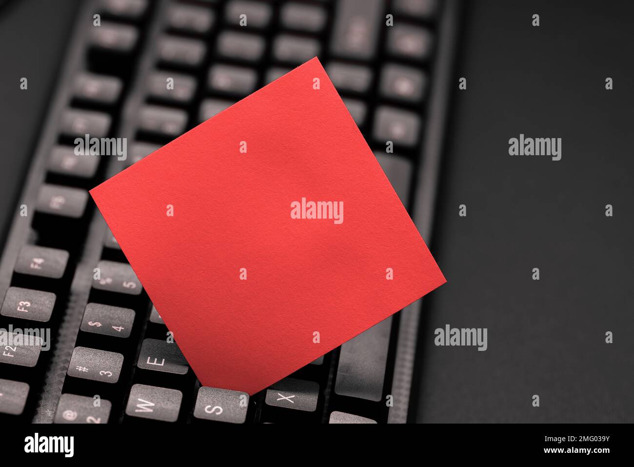 Colored sticker lying on keyboard. Important message written over paper. Stock Photo