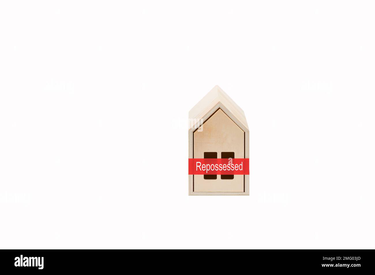 Model house made of wood with red tape and Repossessed message on a plain white background. Rising mortgage interest rates concept. Stock Photo