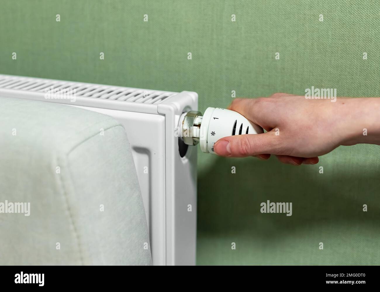 Hand adjusting radiator, turning it on or off. Heat, energy consumption