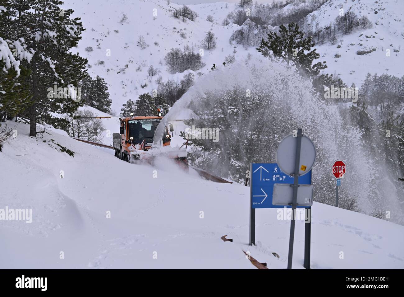 A driver with a snow plow vehicle breaks through the snow-covered road ...