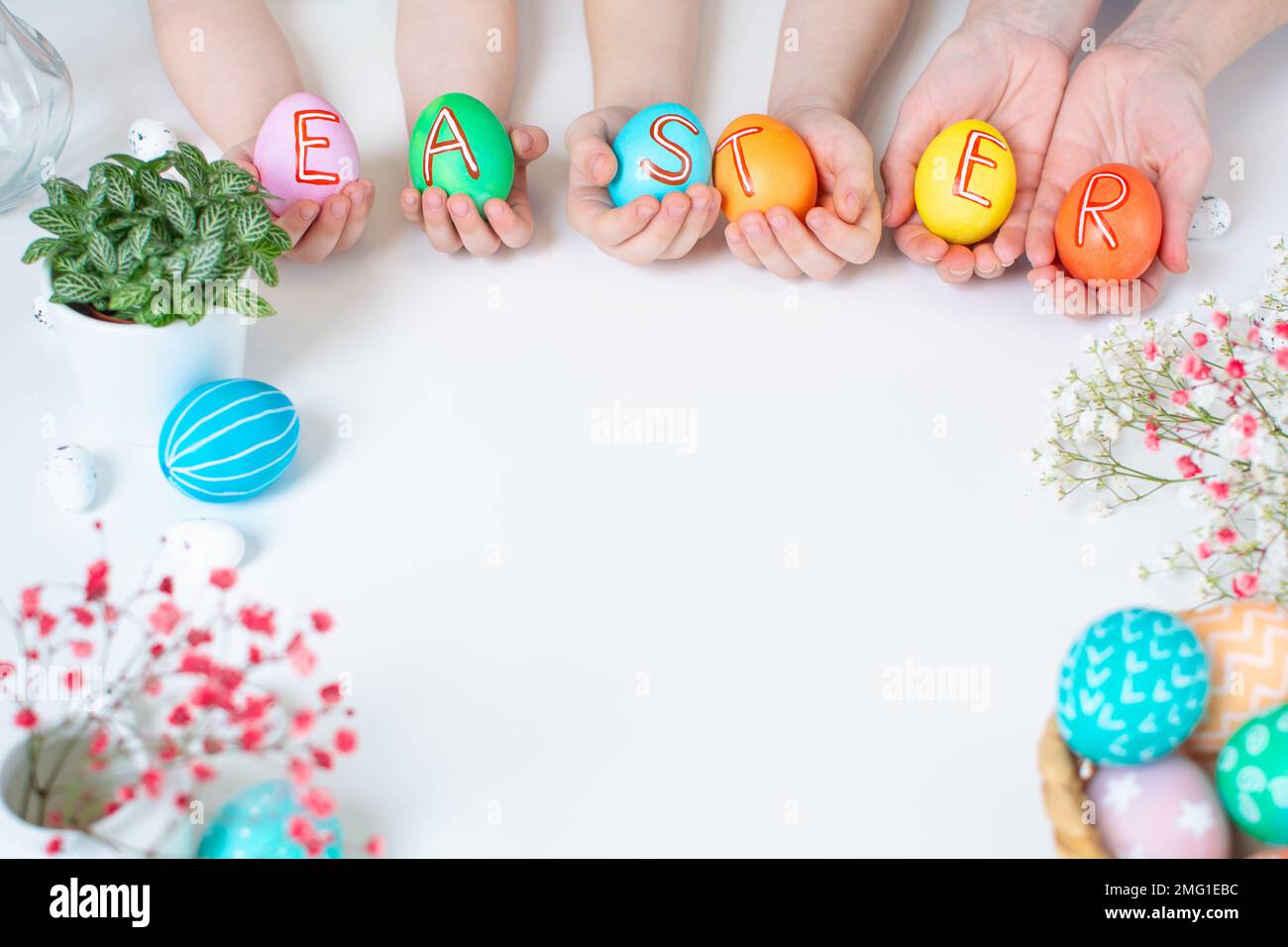 Colorful Easter eggs in hands with text. Holiday flat lay with copy space Stock Photo