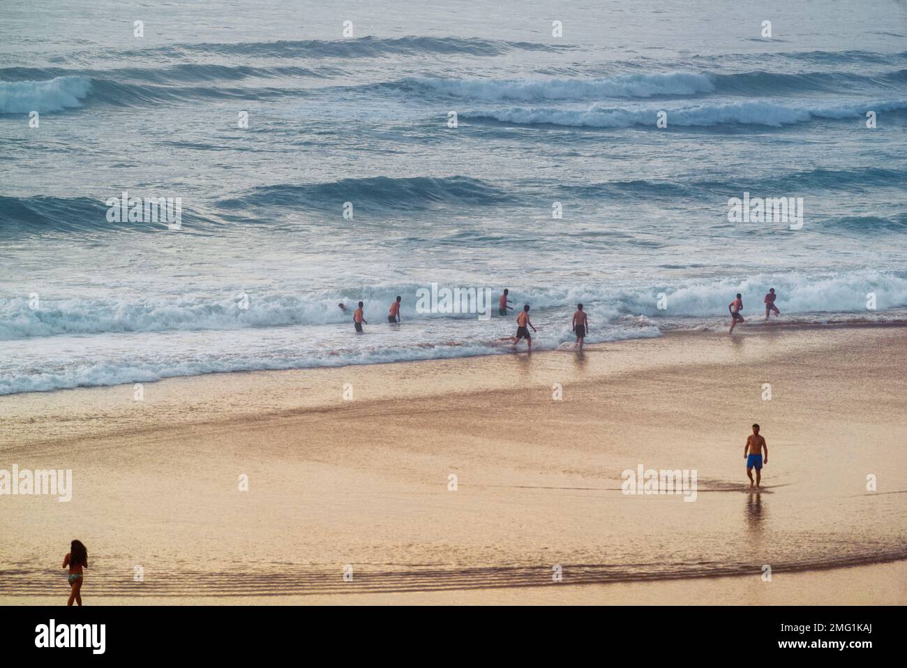 Young boys and girls in swimsuits playing in the sand at the edge of the Cantabrian Sea with mist on the beach of Canallave, Liencres, Cantabria. Stock Photo