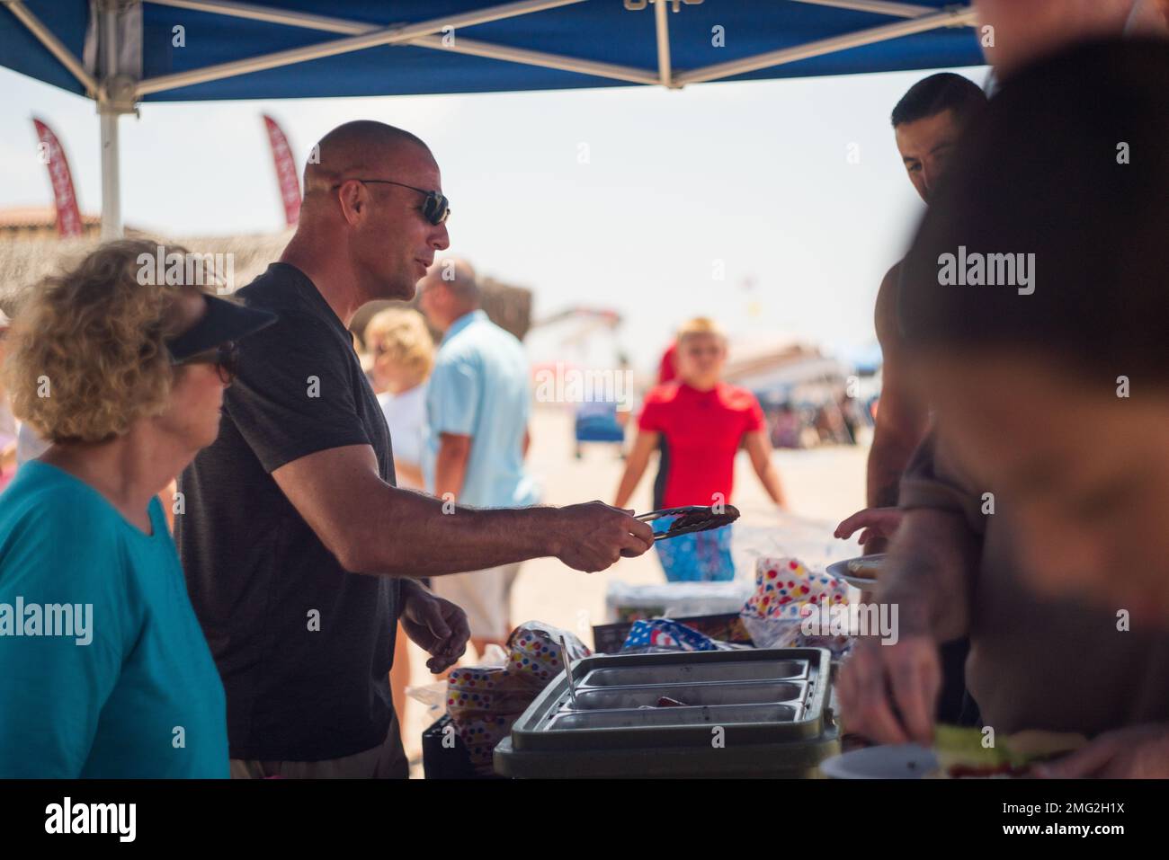 U.S. Marine Corps Col. Sean Dynan, commanding officer of the 15th Marine Expeditionary Unit (MEU), serves burgers to Marines and families at the 15th MEU Beach Bash at Del Mar Beach, Marine Corps Base Camp Pendleton, California, August 20, 2022. The 15th MEU beach bash is an event that brings families, currently serving members of the 15th MEU, and 15th MEU veterans together to build camaraderie, engage in friendly competition and stay connected to our veteran community. Stock Photo