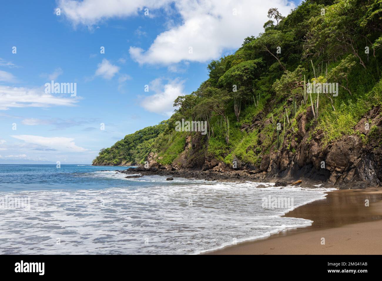 Waves wash on the shore of the vibrant green coast along the Gulf of Papagayo, Playas del Coco, Guanacaste Province in northwestern Costa Rica. Stock Photo