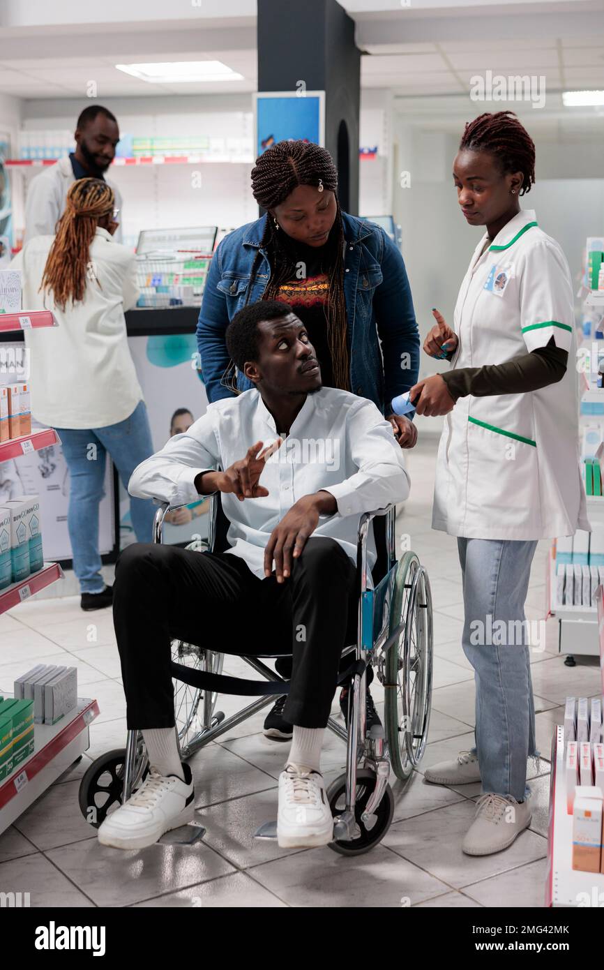 Pharmacist explaining african american customer in wheelchair vitamins  instruction in drugstore. Man with physical impairment and social worker  buying nutritional supplements, all black team Stock Photo - Alamy