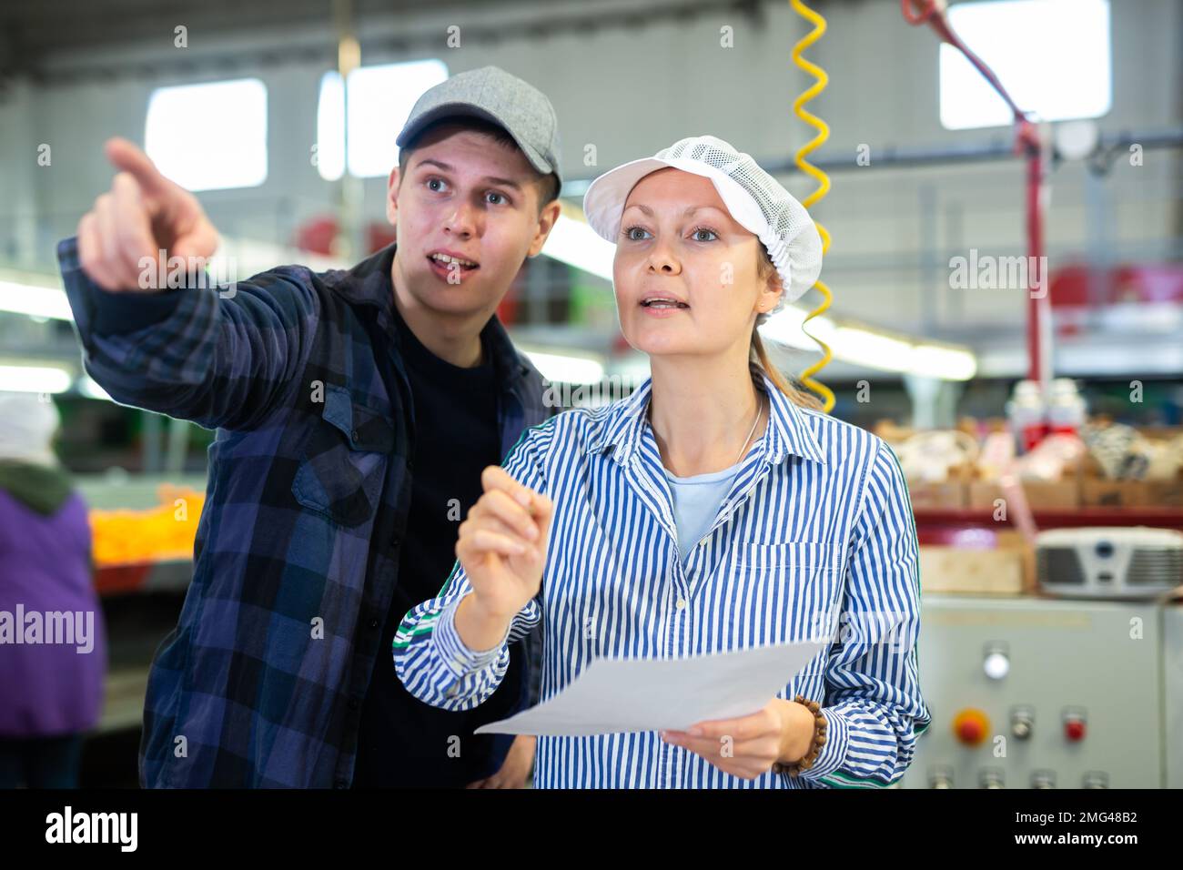 Female supervisor talking to young foreman of citrus sorting factory Stock Photo