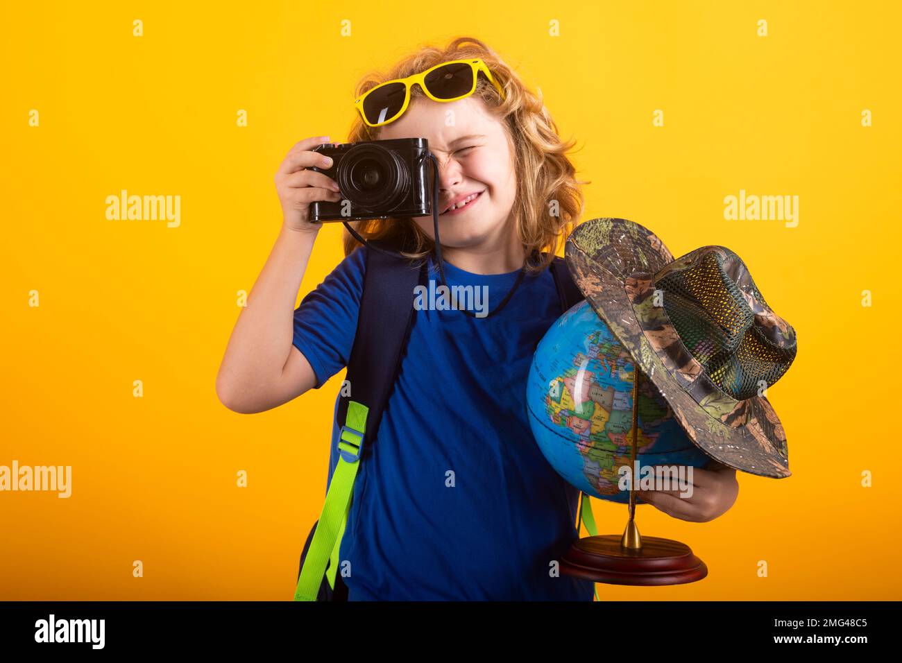 Travel and adventure concept. Little child boy tourist explorer with globe world. Discovery, exploring and education. Studio isolated portrait. Stock Photo