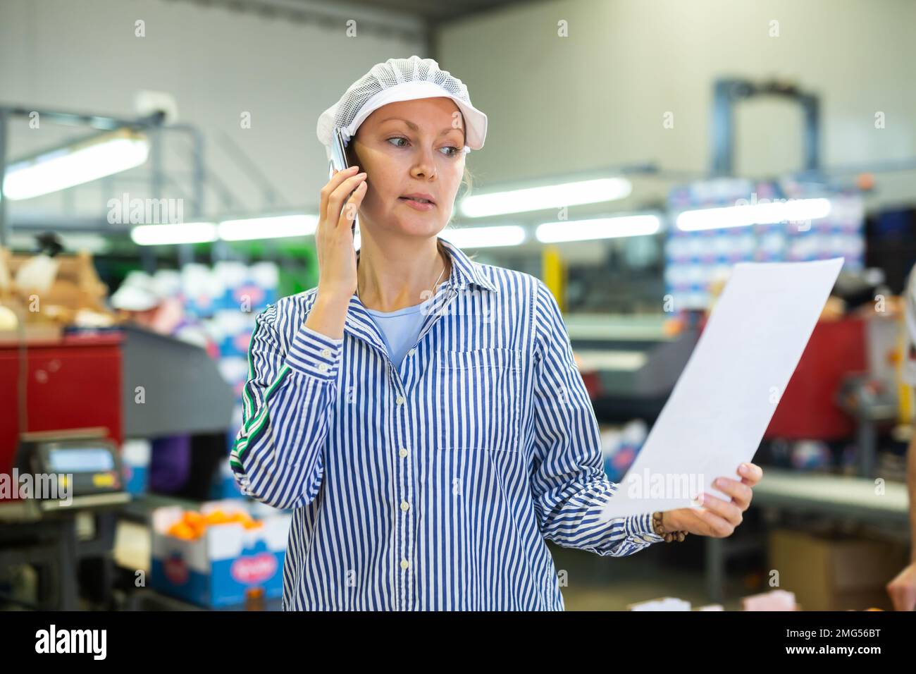 Fruit sorting factory forewoman with papers talking on phone Stock Photo