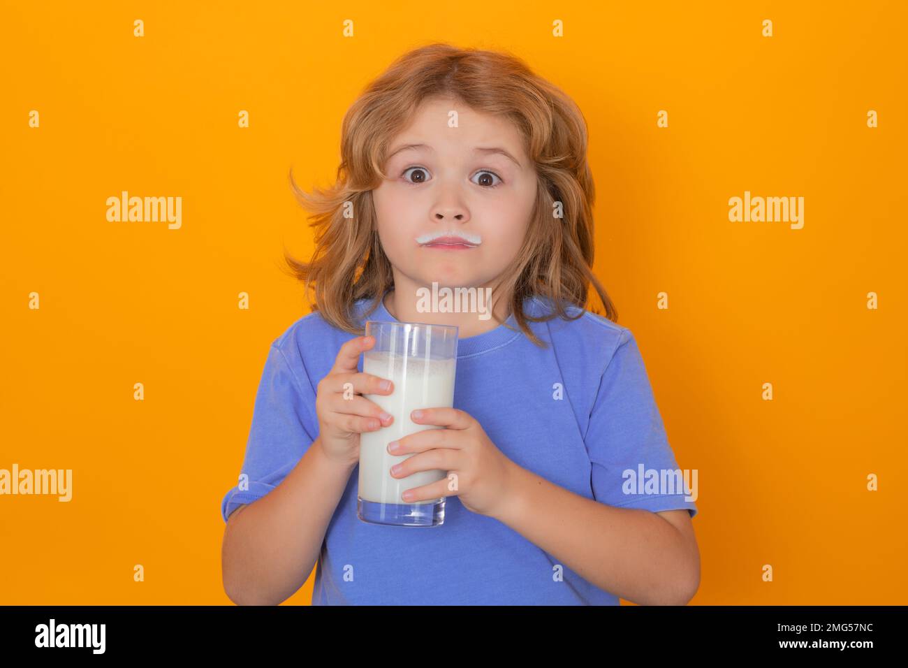Dairy milk. Kid drinking milk isolated on yellow. Little boy child with milk mustache hold glass of milk. Stock Photo