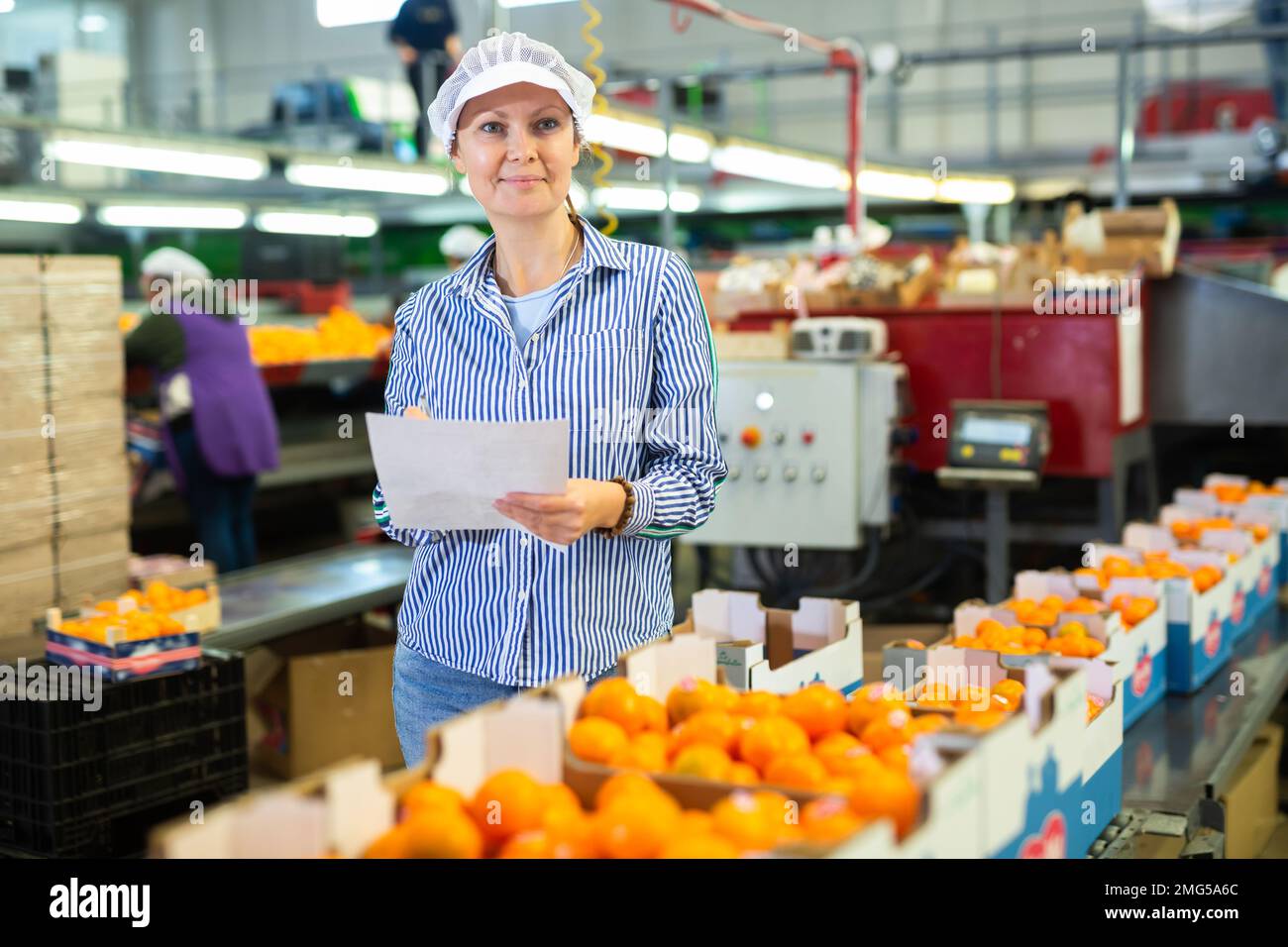 Processing Female Employee Positive female worker fills out a document at a citrus processing ...