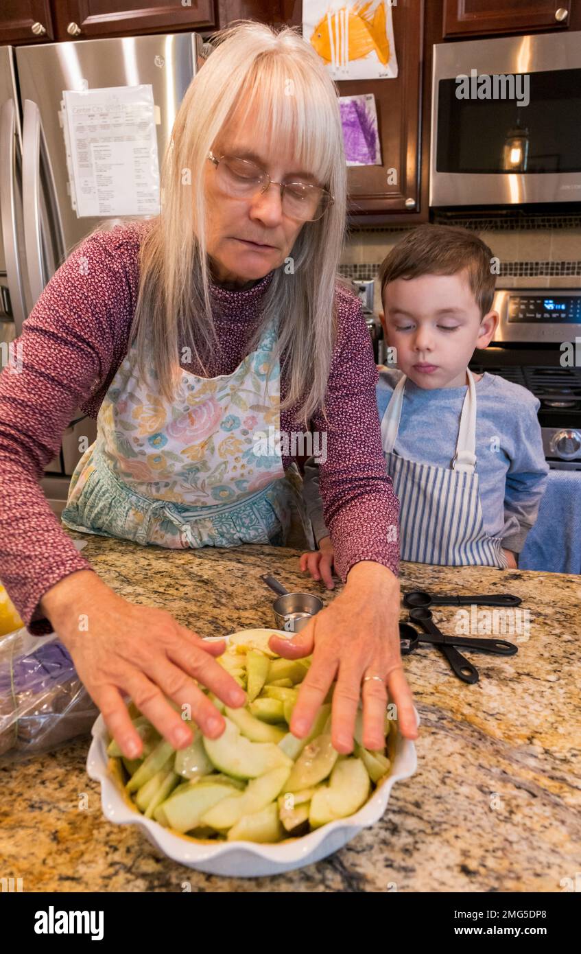 Three year old boy helping grandmother bake a Thanksgiving holiday apple pie; Philadelphia; Pennsylvania; USA Stock Photo