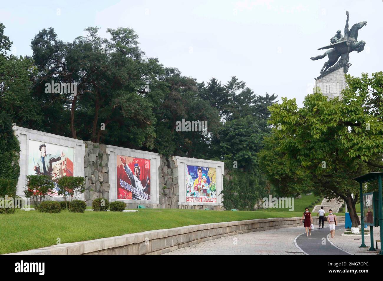 People walk in the street in front of the bronze statue of Chollima in ...