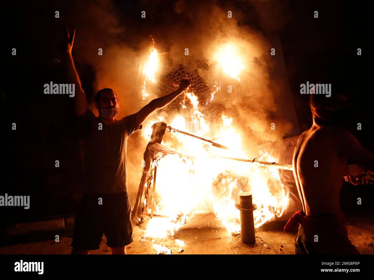 Anti-government protester flashes victory sign, as they burn police ...