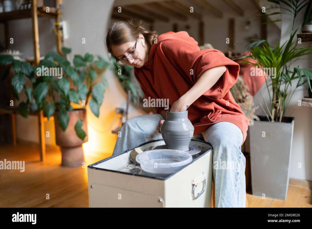 Craftswoman enjoying meditative process of making ceramics, shaping clay on pottery wheel Stock