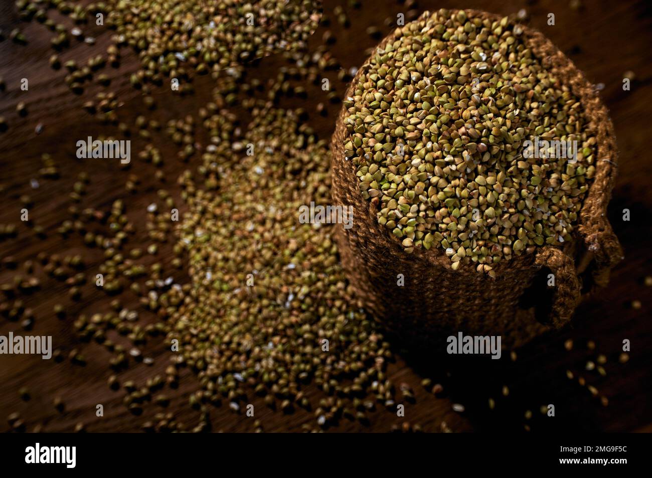 Grains of green raw buckwheat in a jute bag on a wooden table Stock Photo