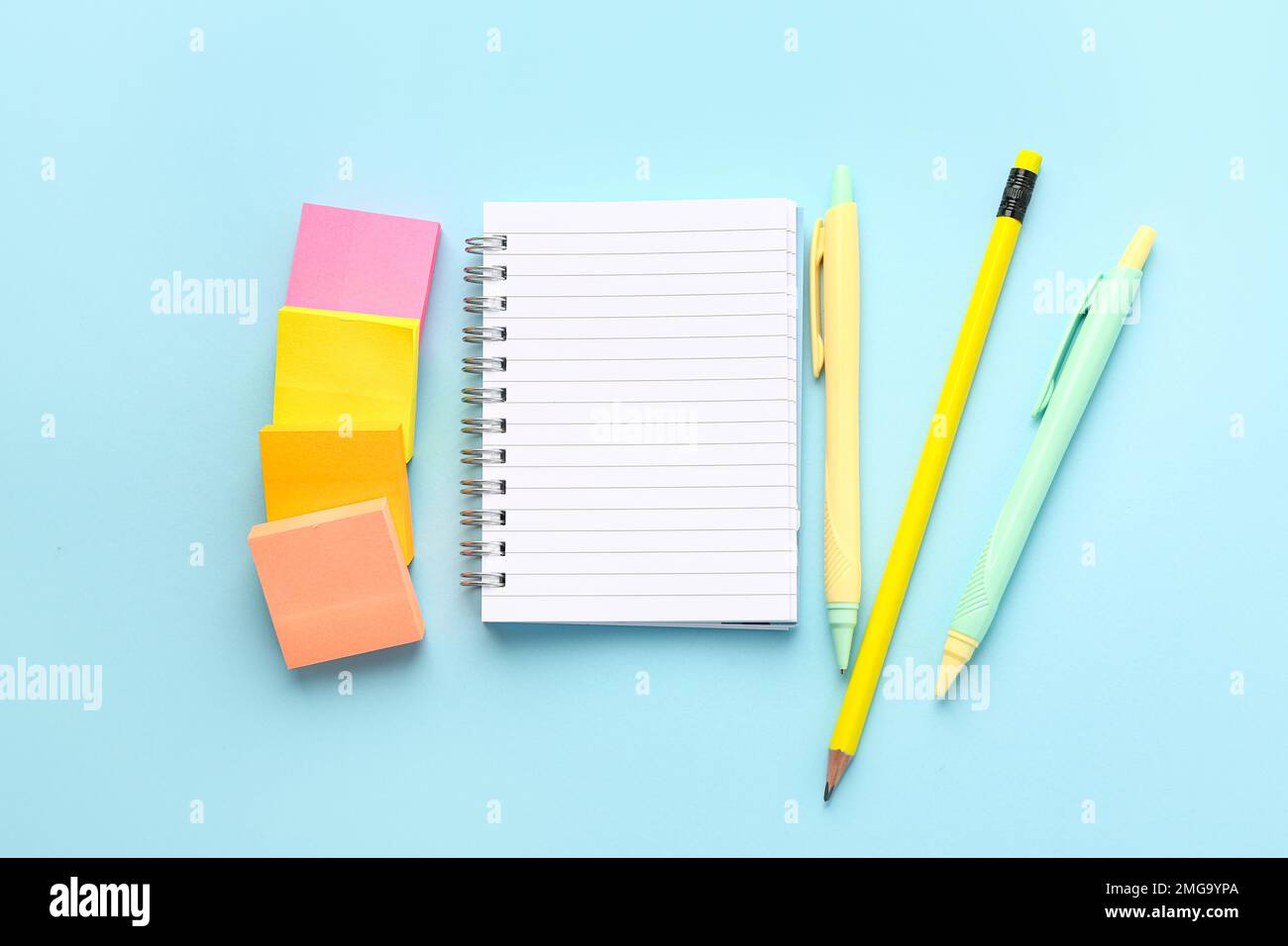 Notebook, sticky notes, pencil and pens on color background Stock Photo